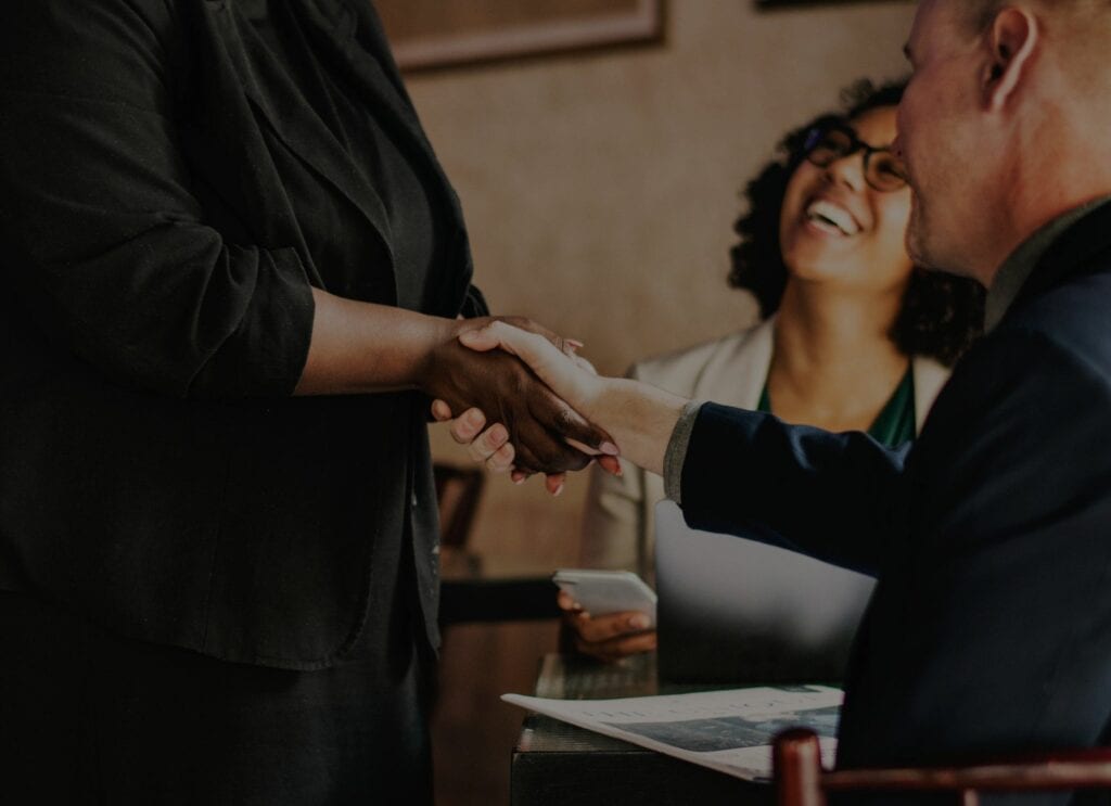 A woman happily shaking hands with a man during a meeting.