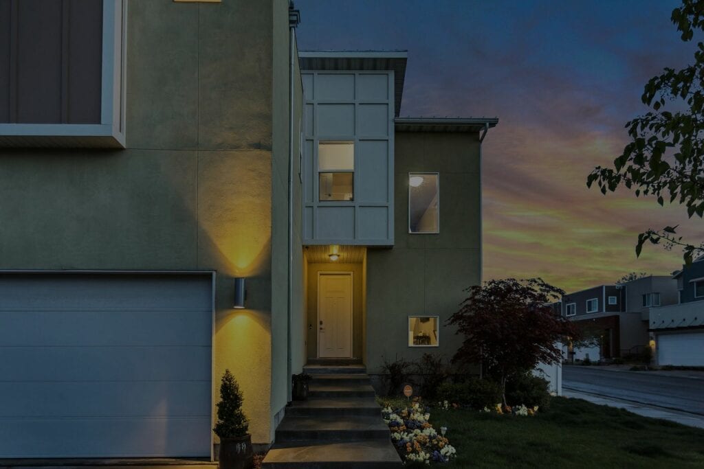 Modern two-story house with warm exterior lighting at dusk.