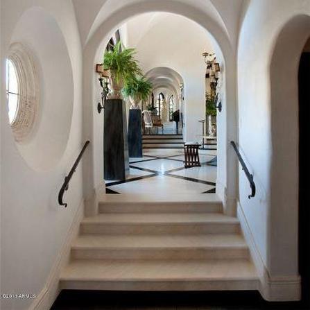 Elegant hallway with arches and plants.